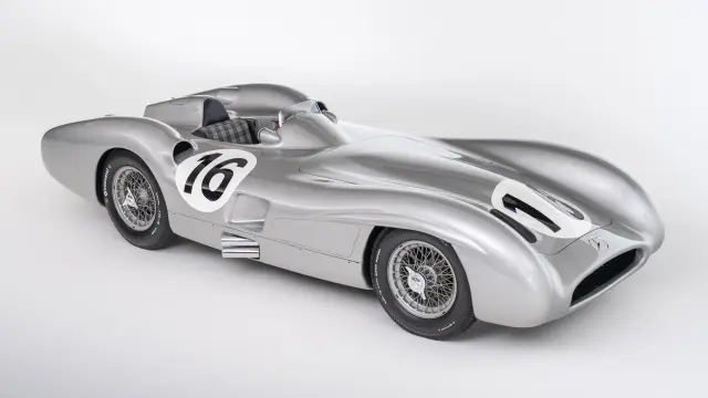 Un automóvil de carreras clásico Mercedes-Benz de color plata, con el número 16 en el lateral, fotografiado sobre un fondo blanco liso.