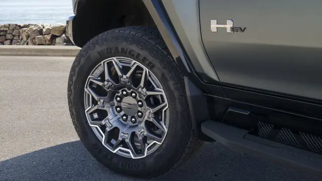 Close-up of front driver-side 2024 GMC HUMMER EV SUV 22-inch wheel with premium painted aluminum finish and selective machining.