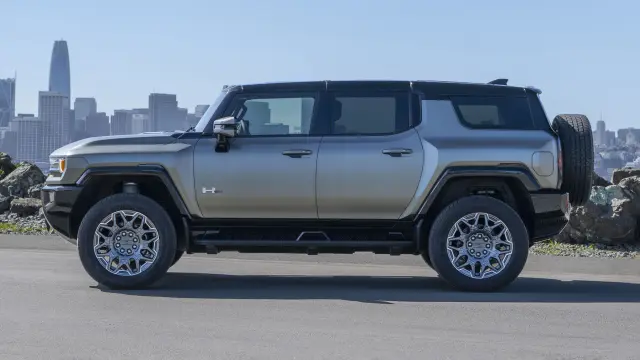 2024 GMC HUMMER EV SUV in Moonshot Green Matte parked in front of the San Francisco skyline.