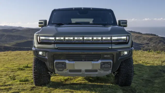 Head-on shot of the 2024 GMC HUMMER EV SUV in Moonshot Green Matte, showcasing robust front approach skid-plate and dynamic headlights.